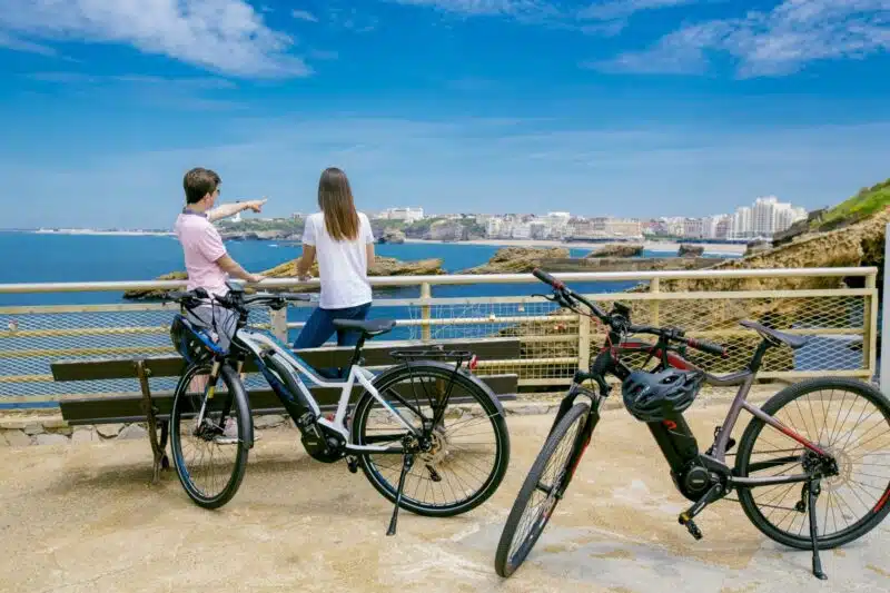 Couple regardant la plage de Biarritz avec vélos VAE garés sur l'esplanade