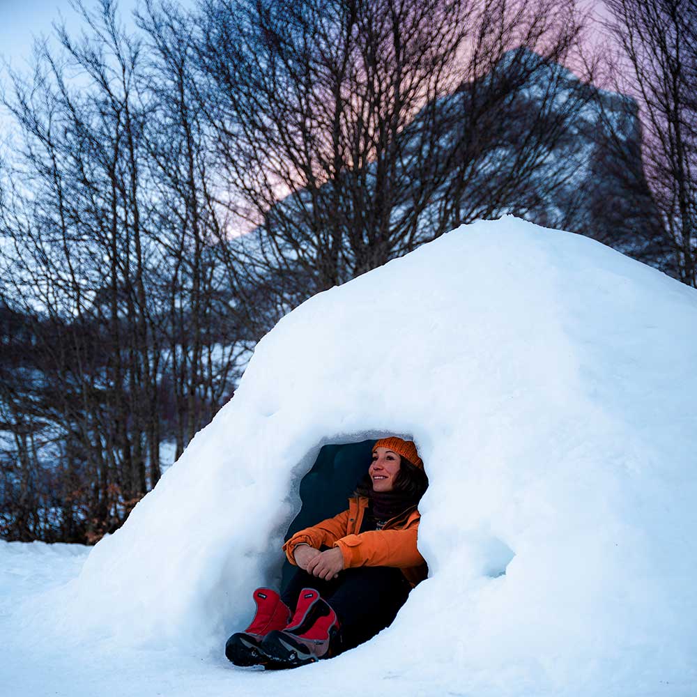 Femme assise dans un igloo à Gourette au coucher du soleil
